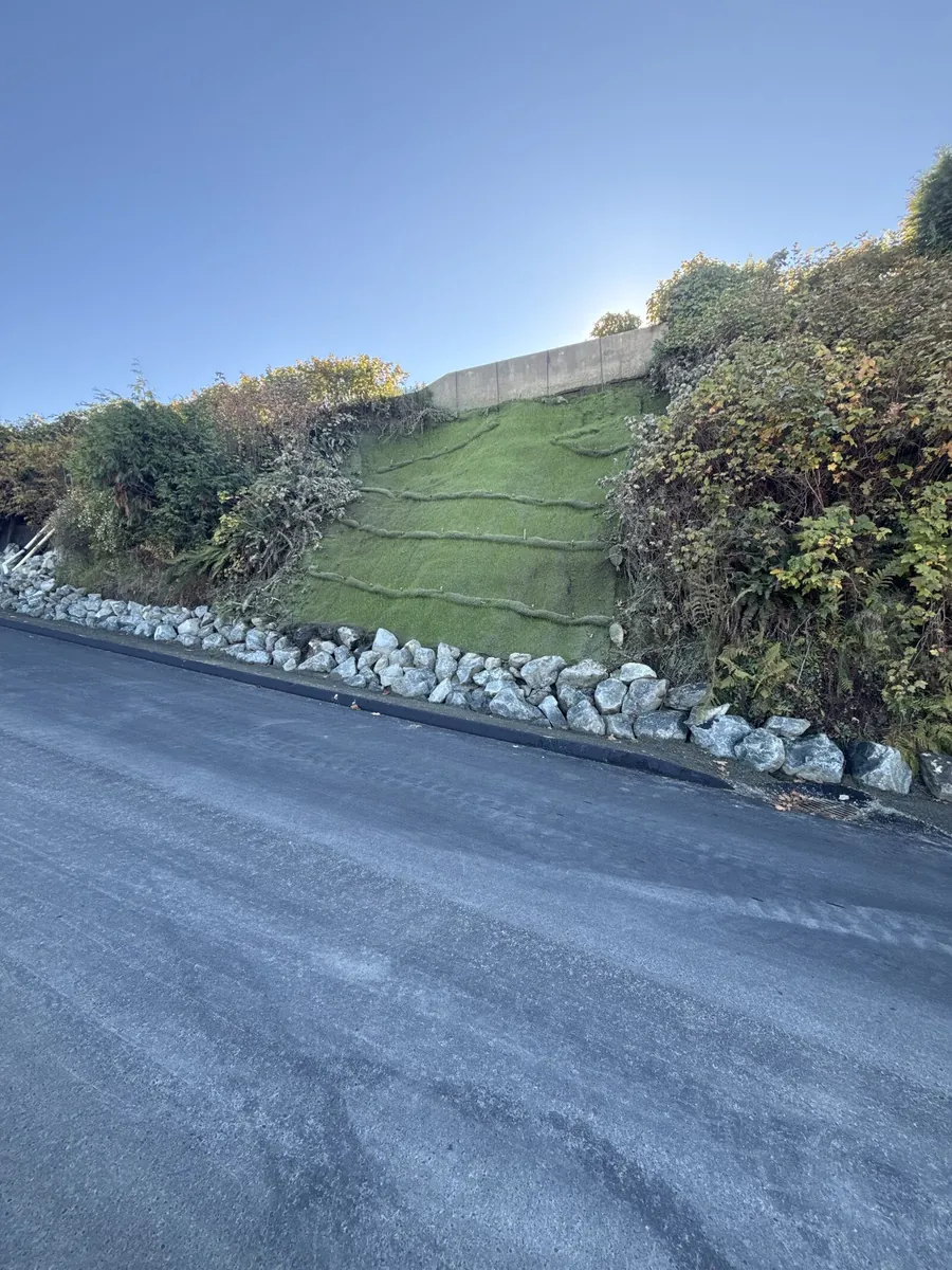 Hydroseeded roadside cut slope stabilized with straw wattles and rock toe protection